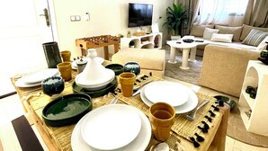 Un coin repas avec une table dressée pour quatre personnes, un canapé, un téléviseur et une plante dans le salon.