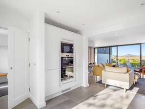 A modern kitchen with built-in appliances and a dining area with a view. - West Haven (Roundstone)