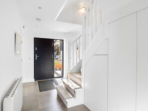 A modern interior with a staircase leading to a dark door, white walls, and a radiator.
