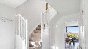 A modern interior with a staircase leading to a dining area with a view.
