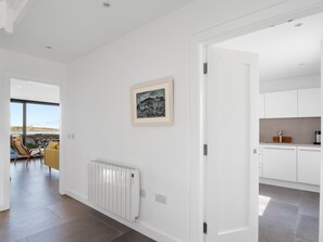 Un interior modern amb una paret blanca, un quadre amb marc, un radiador i una zona de cuina.