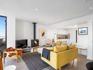 A modern living room with a fireplace, a television, and a sofa. - West Haven (Roundstone)