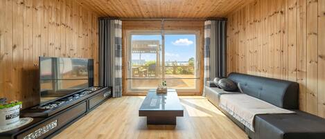 Un salon moderne avec des murs en bois, un téléviseur à écran plat, un canapé et une table basse.