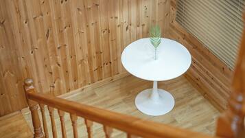 Una escalera con barandilla de madera y un pequeño descansillo con una mesa blanca, un florero de cristal y una planta verde.