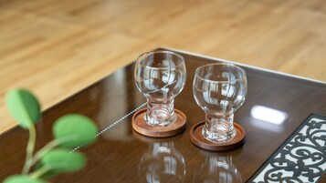 Dos copas de vino de vidrio transparente sobre posavasos de madera, sobre una mesa de madera.