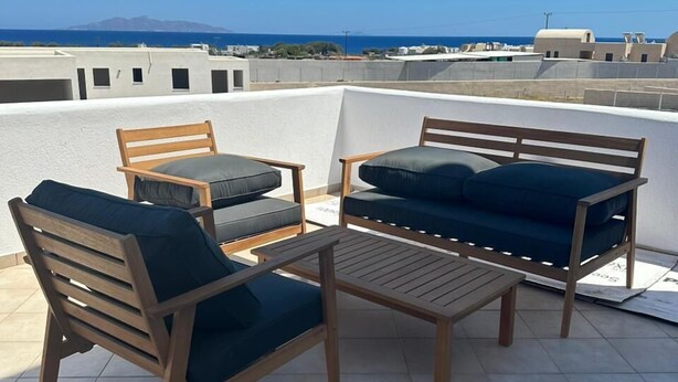 Een terras op het dak met houten meubels en uitzicht op zee.
