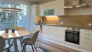 A modern kitchen with white cabinets, a built-in oven, and a large window. - "THREE" - Premium Apartments Seekirchen, modern and central, close to the lake (Seekirchen)