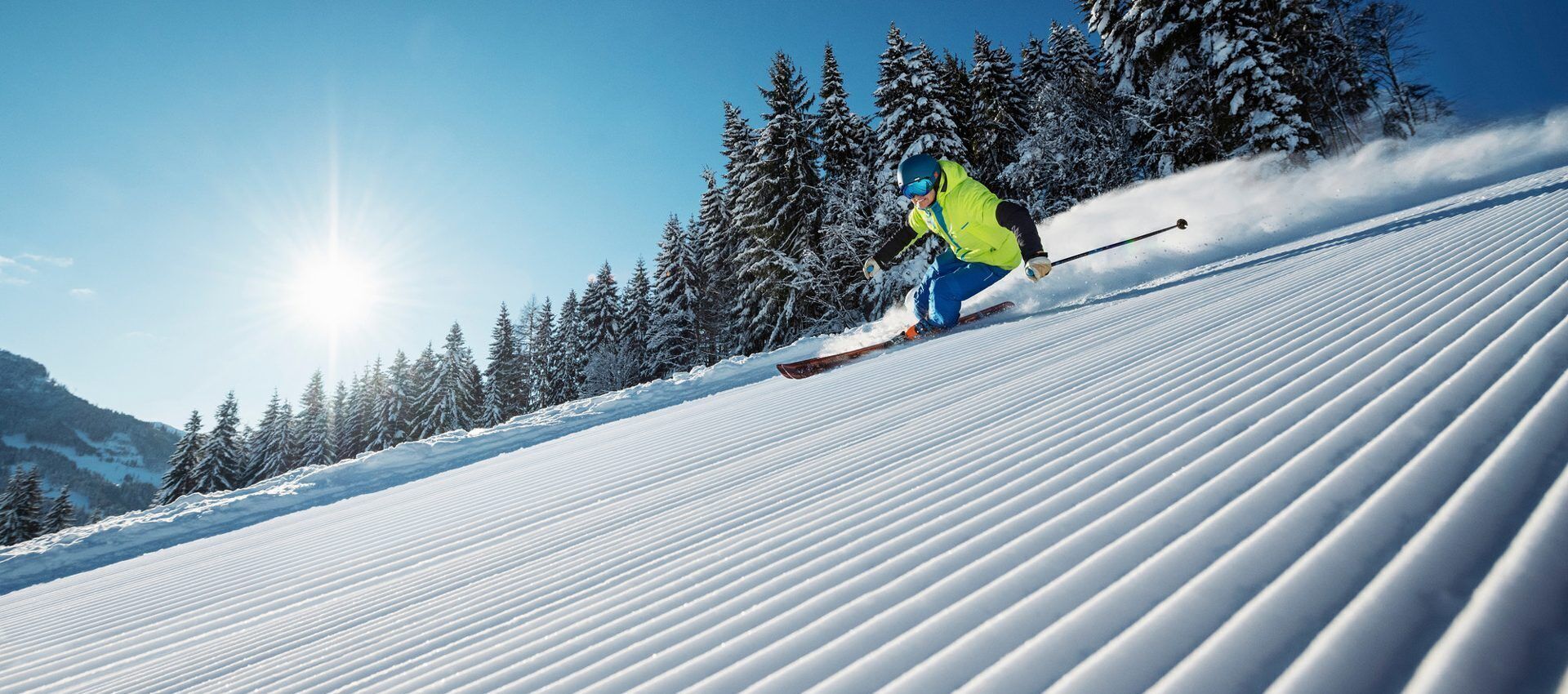 A person skiing down a snow-covered slope with trees in the background.