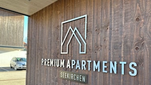 A wooden wall with a logo and text for "Premium Apartments" in Seekirchen. - "THREE" - Premium Apartments Seekirchen, modern and central, close to the lake (Seekirchen)