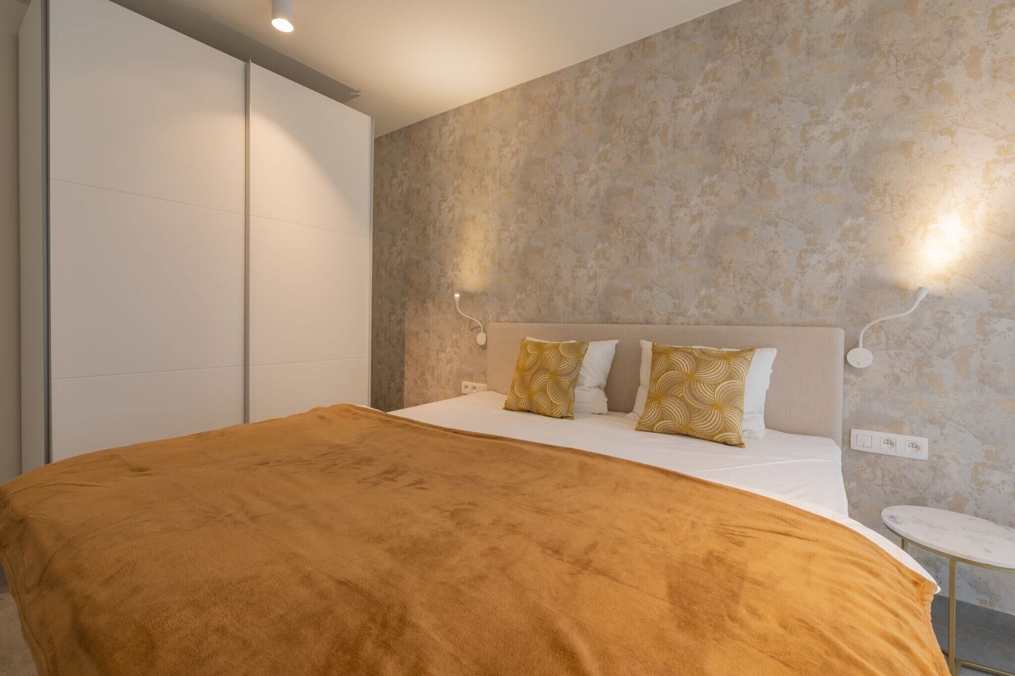 A bedroom with a bed, a bedside table, and a wardrobe.