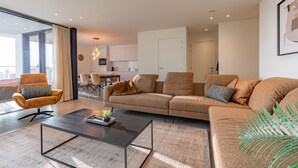 A modern living room with a sofa, armchair, and coffee table. There is a dining area with chairs and a table in the background. - Apartment in Belgium near Marina Nieuwpoort (Nieuwpoort)
