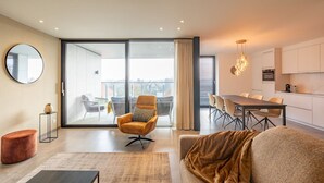 A modern living room with a sofa, a round mirror, and a dining area with a table and chairs. - Apartment in Belgium near Marina Nieuwpoort (Nieuwpoort)