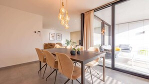 A modern dining area with a large table, chairs, and pendant lighting. - Apartment in Belgium near Marina Nieuwpoort (Nieuwpoort)