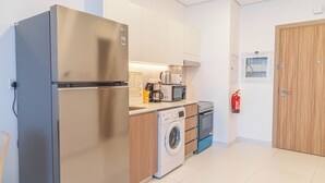 Una cucina compatta con frigorifero in acciaio inossidabile, lavatrice, forno a microonde e macchina per il caffè.