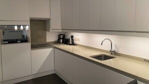 Een moderne keuken met witte kasten, een roestvrijstalen spoelbak en een inbouwoven.