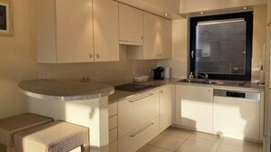 Una cocina moderna con armarios blancos, encimera de granito y lavavajillas integrado.
