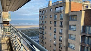 Un edificio de gran altura con varios balcones que dan a una playa.