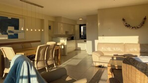 Una sala de estar moderna con sofá, sillas, una mesa de comedor y una cocina al fondo.