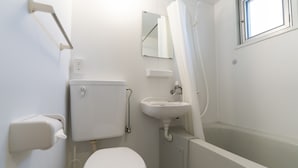 A small, white bathroom with a toilet, sink, and bathtub. - LoveOkinawa – 180° Ocean View Onna 1DK Seaside Stay (Onna)