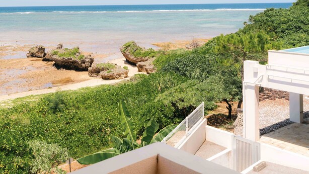A balcony with a view of a beach and ocean. - LoveOkinawa – 180° Ocean View Onna 1DK Seaside Stay (Onna)