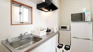 A compact kitchen with a stainless steel sink, a microwave, a toaster, and a refrigerator. - LoveOkinawa – 180° Ocean View Onna 1DK Seaside Stay (Onna)