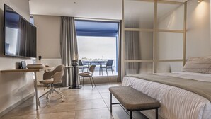 Une chambre d’hôtel moderne dotée d’un grand lit, d’un bureau avec une chaise, d’une télévision et offrant une vue sur un pont.