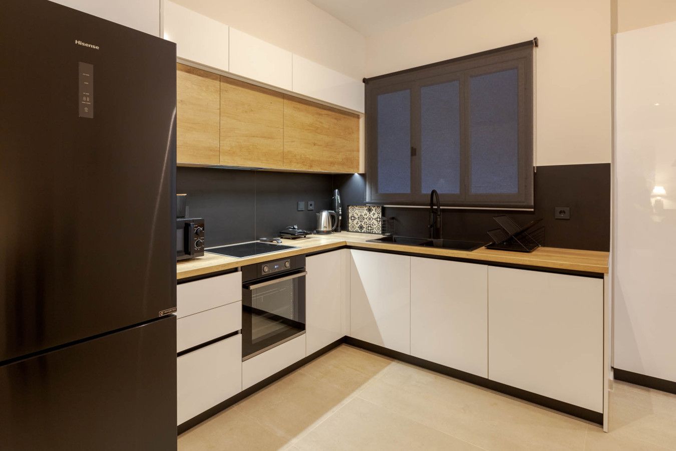 Une cuisine moderne équipée d’un four encastré, d’un réfrigérateur, d’un évier et d’une fenêtre située au-dessus du plan de travail.