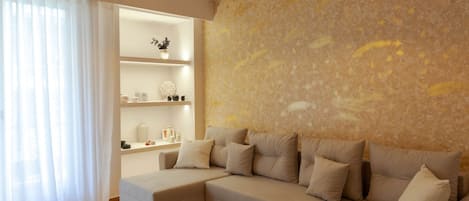 Una sala moderna con un sofá seccional, una estantería empotrada y una pared grande con textura.