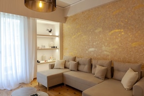 A modern living room with a sectional sofa, a built-in shelf unit, and a large textured wall.