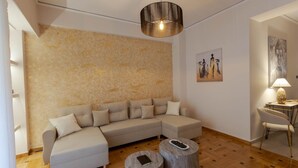 Ein modernes Wohnzimmer mit einer Eckcouch, zwei runden Holztischen, einer Pendelleuchte und Bildern an den Wänden.