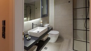 Ein modernes Badezimmer mit einem weißen Waschbecken, einer schwarzen Arbeitsplatte und einer Duschkabine aus Glas.