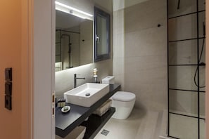 Een moderne badkamer met een witte wastafel, een zwart aanrechtblad en een douchecabine van glas.