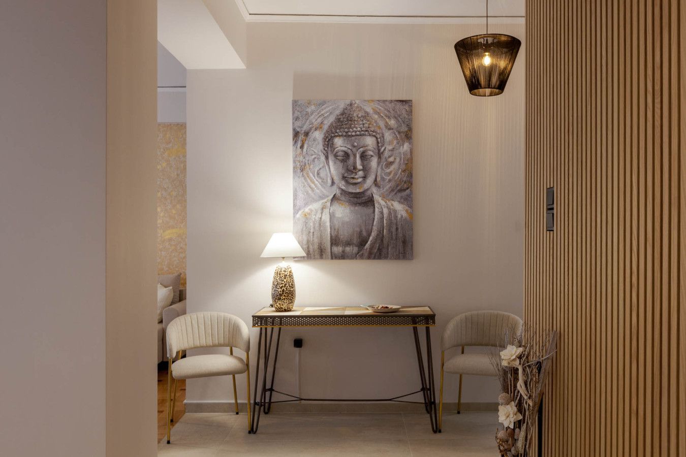 Un interior moderno con un cuadro de Buda, una mesa con una lámpara y dos sillas.