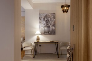 A modern interior with a Buddha painting, a table with a lamp, and two chairs.