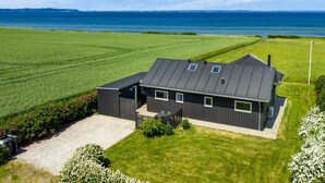 Ein modernes Haus mit geneigtem Dach, großen Fenstern und Blick aufs Meer.