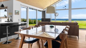 Ein großzügiger Wohnbereich mit einem großen Holztisch und Stühlen, einem Sofa und Blick auf den Ozean.