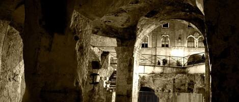 An interior with stone arches and a staircase leading to a balcony.