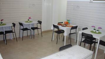 A dining area with multiple tables and chairs, some with flowers on the table centerpieces.
