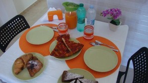 Taula de l'esmorzar amb plats de menjar, un croissant, una porció de pizza i un got de suc d'aranja.