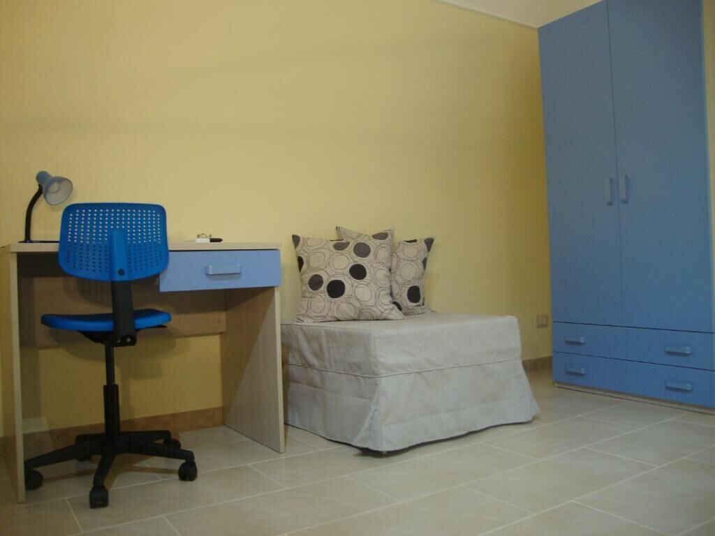 Una habitación con escritorio, silla, cama y armario.