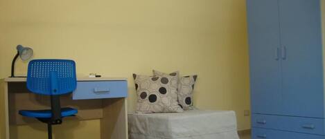 Una habitación con escritorio, silla, cama y armario.