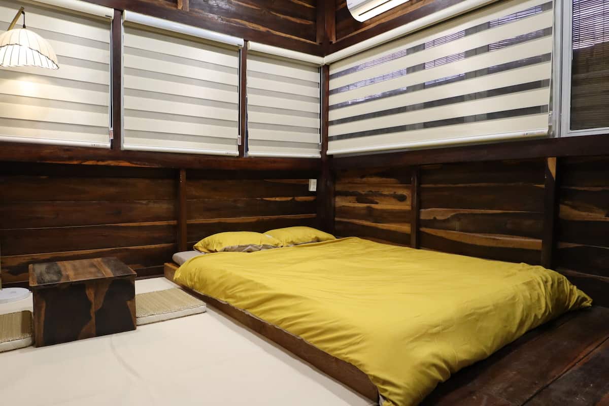Una habitación tipo cabaña de madera con una cama, una mesita y una lámpara.