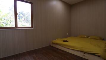 A bedroom with a single bed, a window, and wooden flooring.