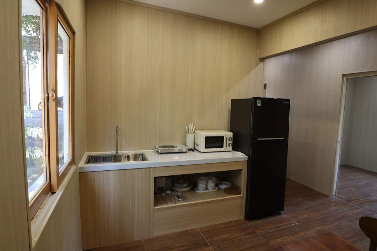 Una cocina compacta con microondas, refrigerador, lavamanos y armarios de madera.