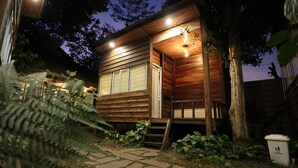 Eine Holzhütte mit Veranda, einer Leiter und einem Mülleimer.