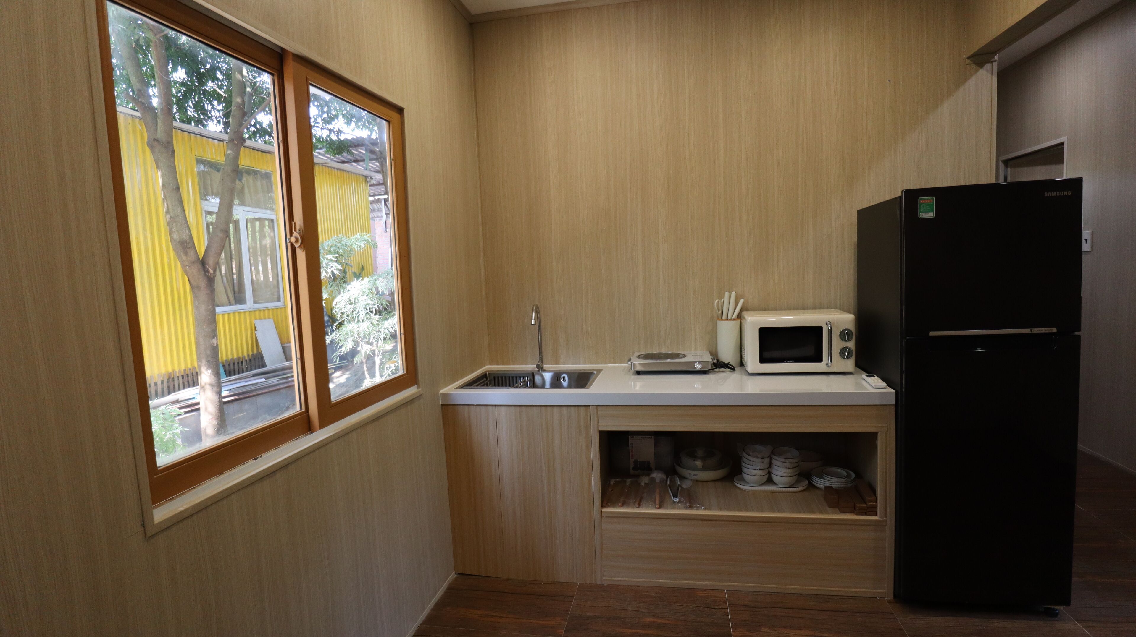A compact kitchen with a built-in microwave, a sink, and a black refrigerator.