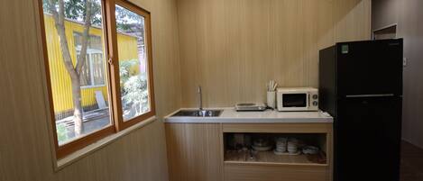 A compact kitchen with a built-in microwave, a sink, and a black refrigerator.