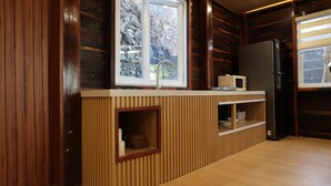 Eine kleine Küche mit Holzwänden, einer eingebauten Spüle, einer Mikrowelle und einem Kühlschrank.