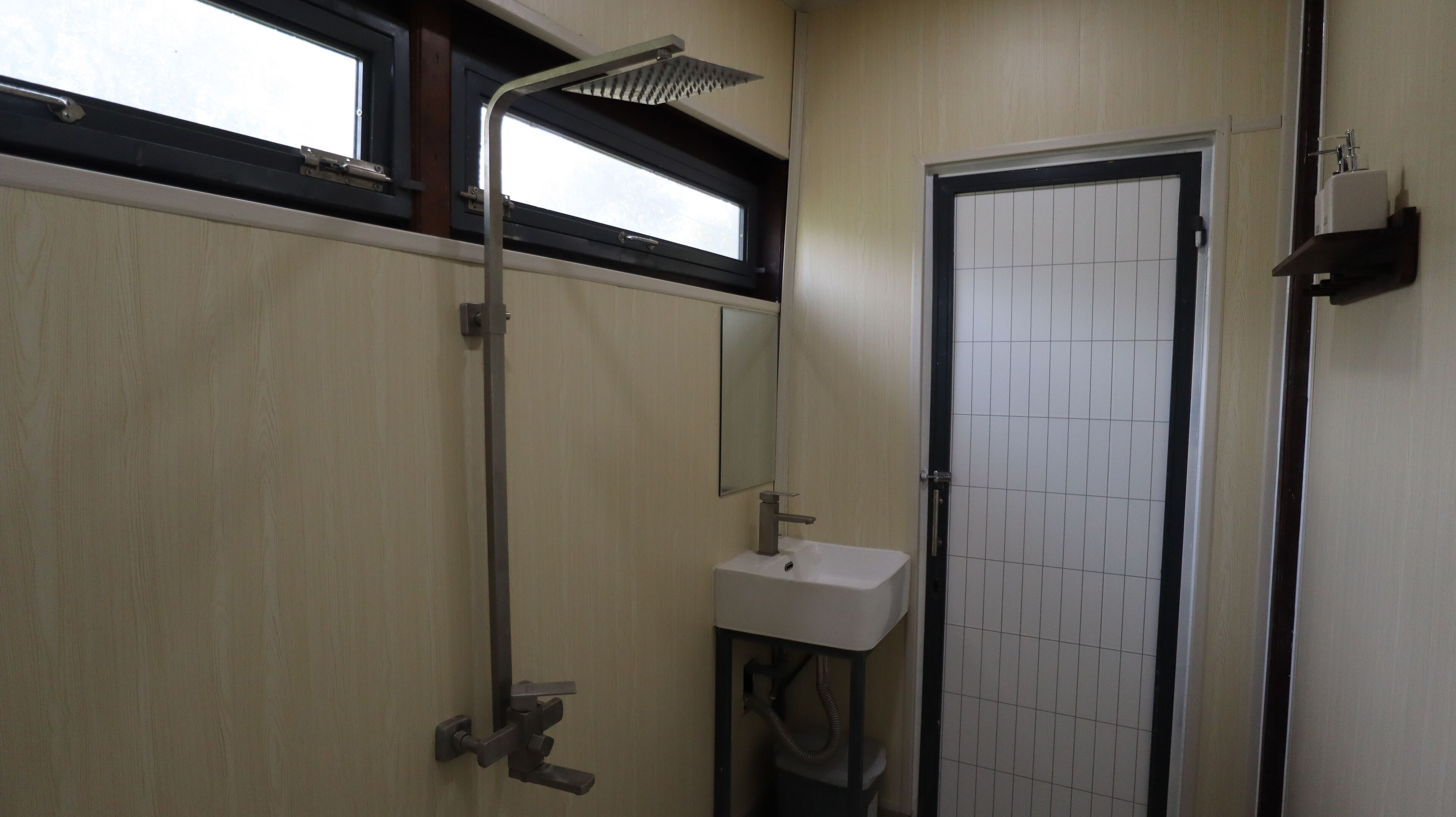 Un bagno piccolo con una finestra, un lavandino e una porta.