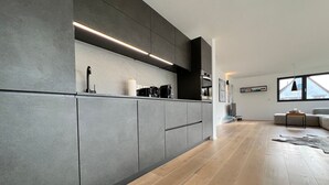 A modern kitchen with grey cabinets, a built-in oven, and a coffee maker. - LAKE Loft Azur - in the Überlingen spa district (Überlingen)